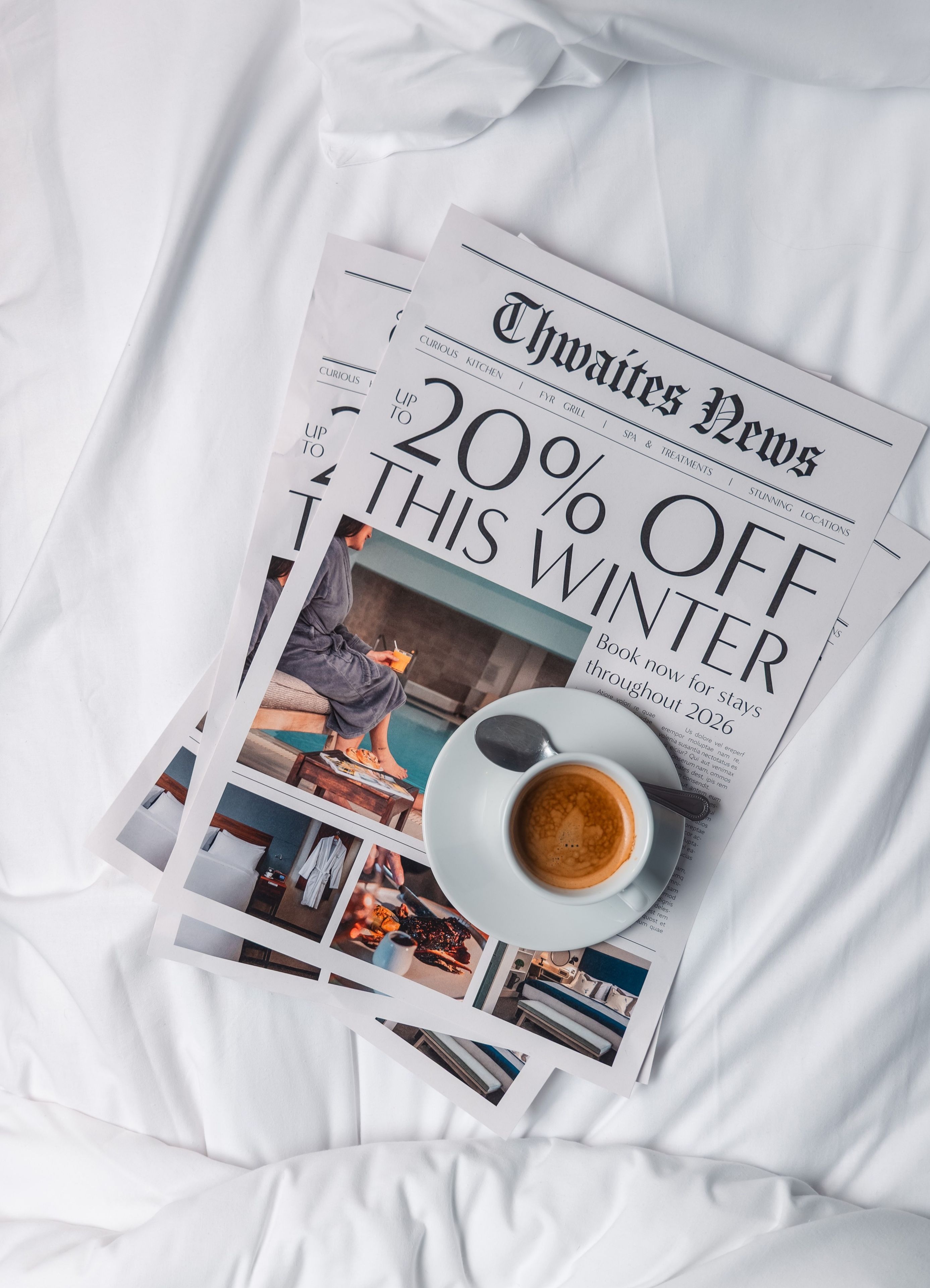 Magazine on a hotel bed with a cup of coffee that reads "Up to 20% off this winter"