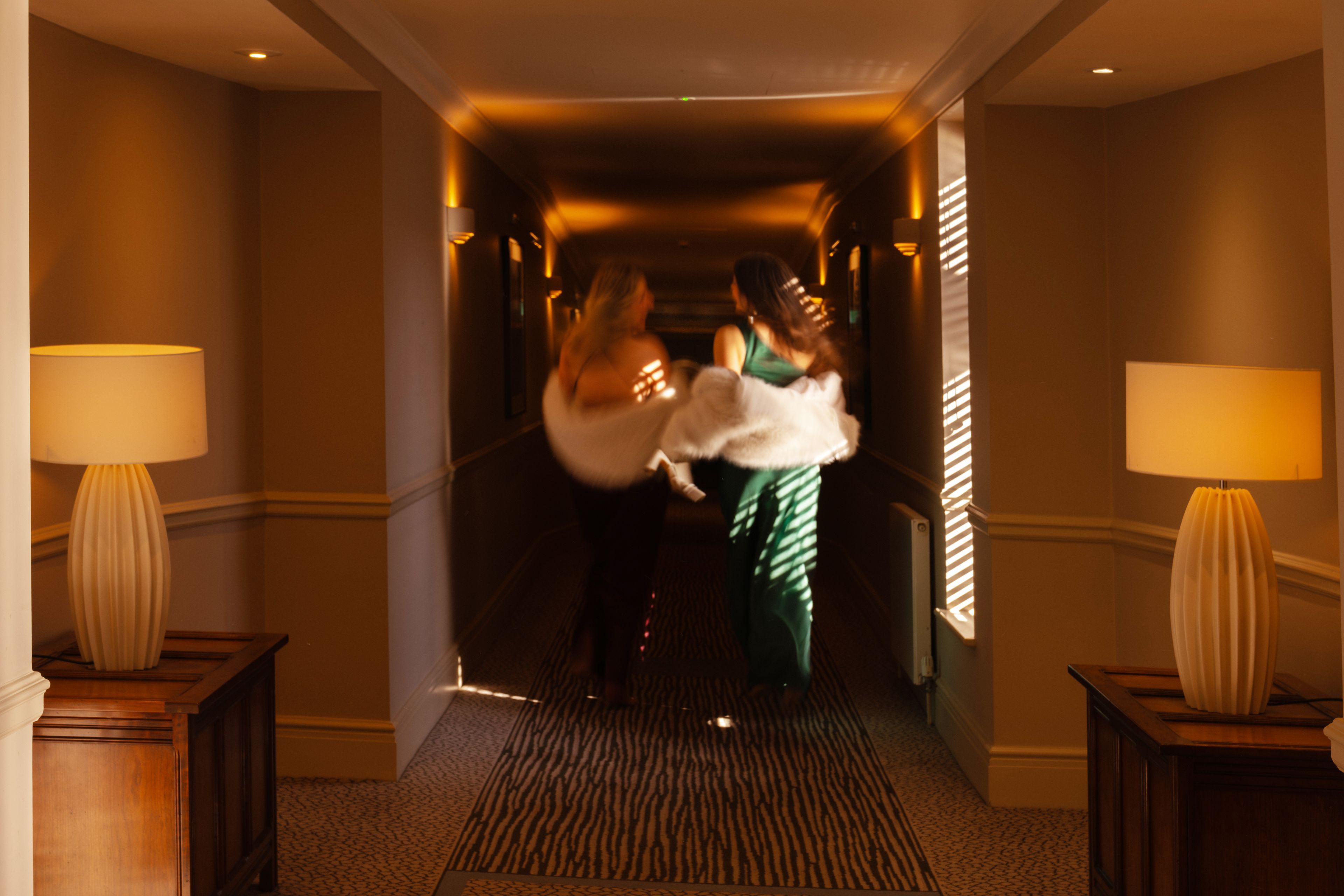 Two girls walking down corridor dressed up for a party night